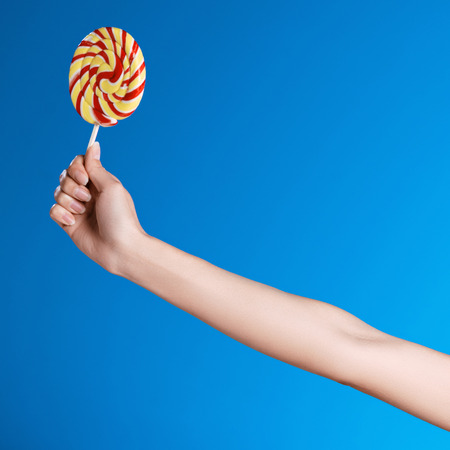 person holding bright lollipop isolated on blueの写真素材