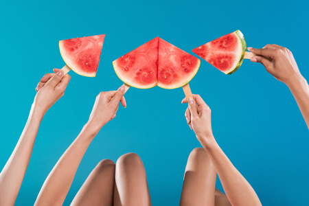 young women holding watermelon pieces on popsicle sticksの写真素材