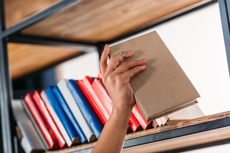 student holding book at bookshelf in libraryの写真素材