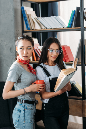 young students with book and cup studying together and smilingの写真素材