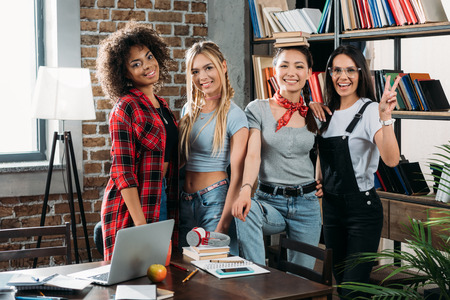 stylish multiethnic women posing together at home libraryの写真素材