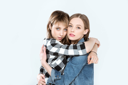young lesbian couple hugging and posing together isolated on blueの写真素材