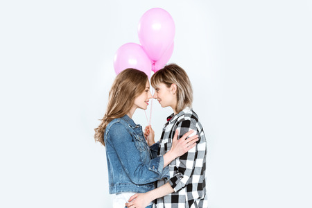 sensual young girlfriends posing together and holding balloons isolated on greyの写真素材