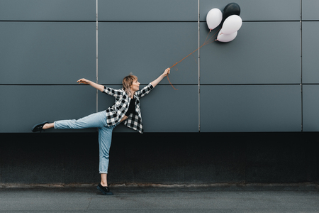 cheerful young woman holding balloons outdoorsの写真素材