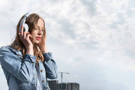pensive woman listening music in headphones under the skyの写真素材
