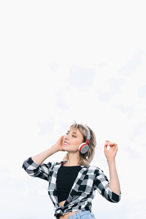 caucasian girl listening music in headphones under the skyの写真素材