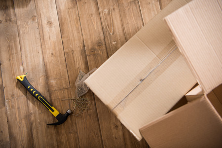 Top view of cardboard boxes with hammer and nails on wooden floorの写真素材