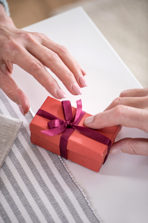 man presenting gift in box with ribbon to his wifeの写真素材