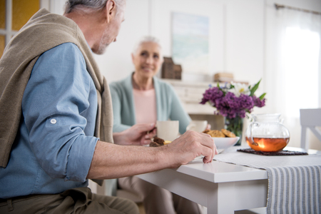 grey haired couple having breakfast at homeの写真素材