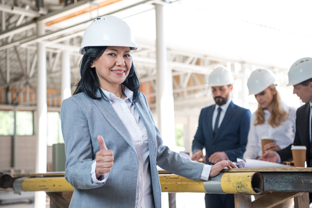 aged asian contractor showing thumb up during meeting at construction siteの写真素材