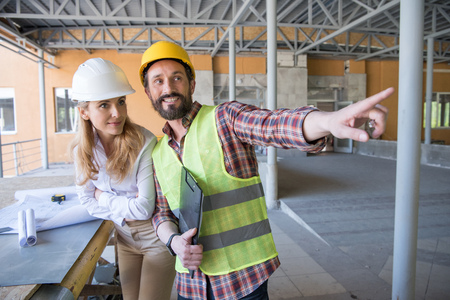 foreman in builder uniform talking with contractor on construction siteの写真素材