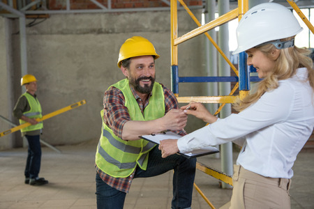 foreman in builder uniform talking with contractor on construction siteの写真素材