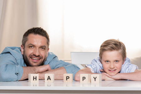Father with son at table and word Happyの写真素材