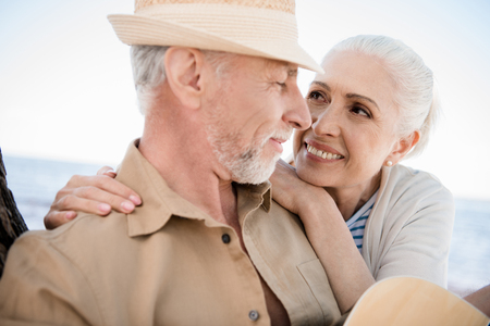 beautiful senior couple embracing and smiling each other outdoorsの写真素材