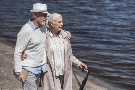 grey haired couple walking on riverside at daytimeの写真素材
