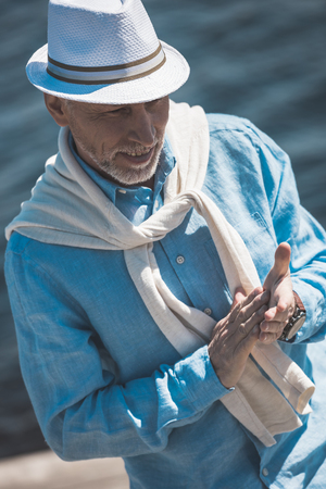 stylish senior man smiling and rubbing hands outdoorsの写真素材