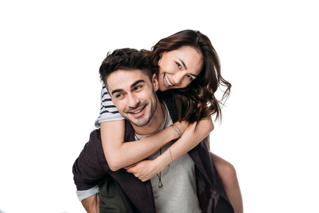 smiling couple doing piggyback isolated on whiteの写真素材