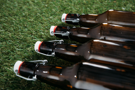 Closeup view of closed glass bottles of beer lying on green grassの写真素材