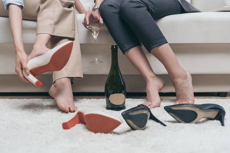 tired women drinking champagne while resting on sofa at homeの写真素材