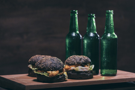 burgers with black bun and bottles on wooden kitchen deskの写真素材