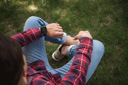 man in casual clothes looking at wristwatch and waiting somebody at parkの写真素材