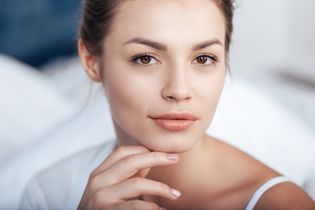 charming young woman in bedの写真素材