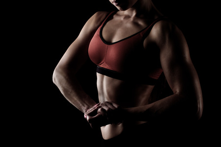 cropped view of sportswoman posing in sportswear and showing her muscular armsの写真素材