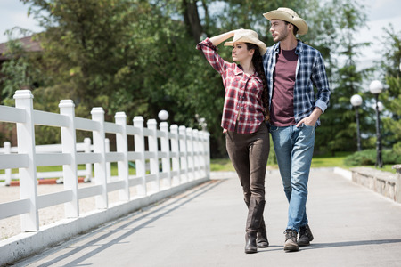 cowboy with his girlfriend walking on pathway in park at daytimeの写真素材