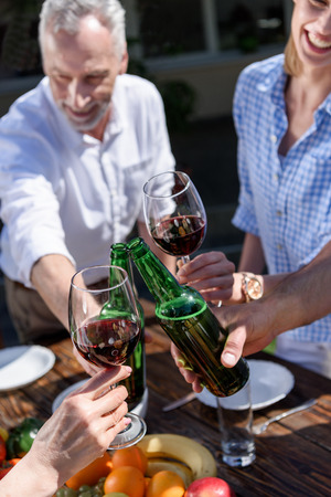 group of people clinking glasses and bottles during picnicの写真素材