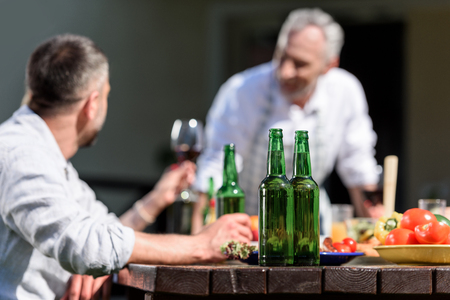 family talking while having lunch on patio at daytime. Selective focus on bottlesの写真素材