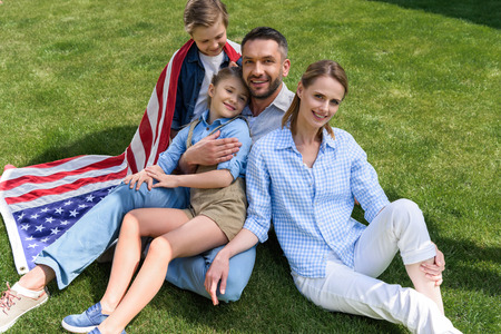 parents and children relaxing on grass with american flag, celebrating 4th july - Independence Dayの写真素材