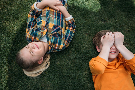 adorable kids sunbathing while lying on grass