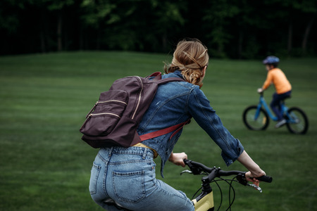 casual woman with backpack riding bicycle at park