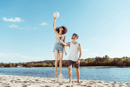 active man and woman playing volleyball on beach togetherの写真素材