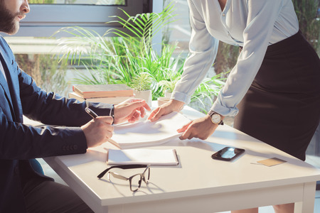 businesspeople signing documents during meeting