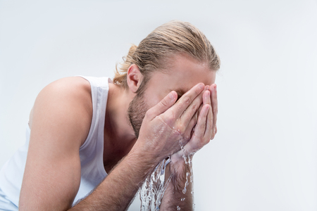 young man washing face at morning isolated on greyの写真素材