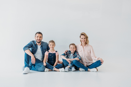 family looking at camera while sitting together on the floorの写真素材