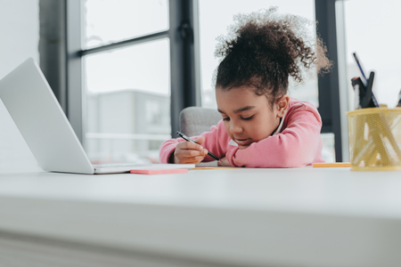 little african american girl using laptop while sitting at office tableの写真素材