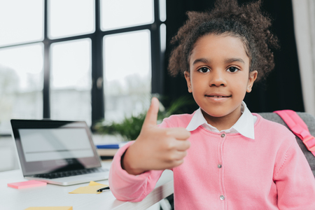 little girl showing thumb up sign and smiling at cameraの写真素材