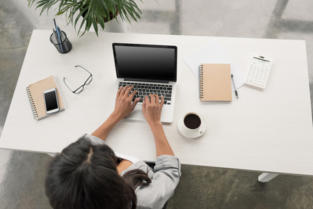 businesswoman using laptop while sitting at workplace in officeの写真素材