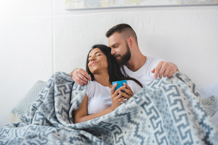 young couple drinking coffee in bed in the morningの写真素材