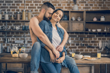young couple hugging while having breakfast at homeの写真素材