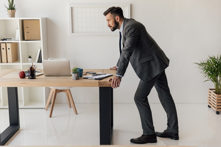 thoughtful businessman standing at table and looking awayの写真素材
