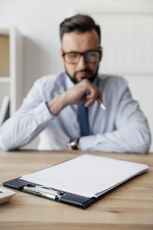 pensive businessman looking at blank papers on tableの写真素材