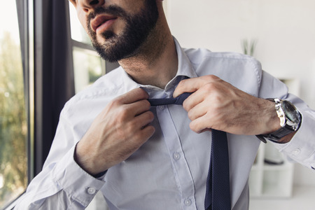 young bearded businessman in shirt adjusting tieの写真素材
