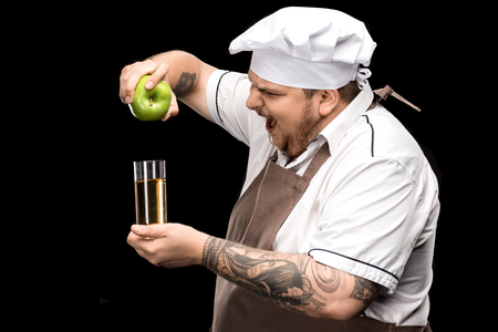 side view of yelling chef holding fresh apple and glass of juiceの写真素材