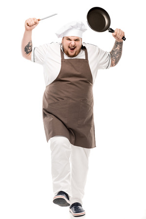 angry chef with frying pan and knife in hands looking at cameraの写真素材