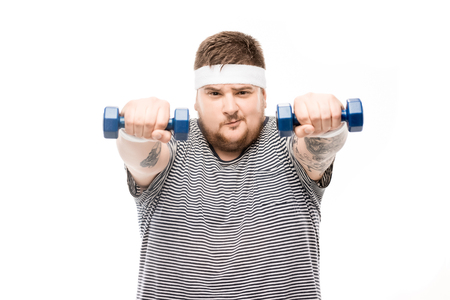 portrait of chubby man exercising with dumbbells and looking at cameraの写真素材