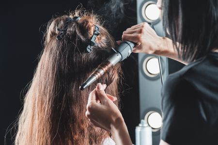 hair dresser using curling iron while styling hairの写真素材