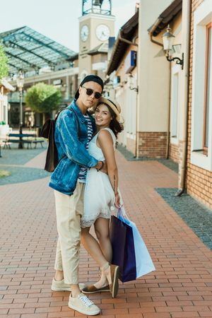 young hipster couple holding shopping bags and hugging on the streetの写真素材